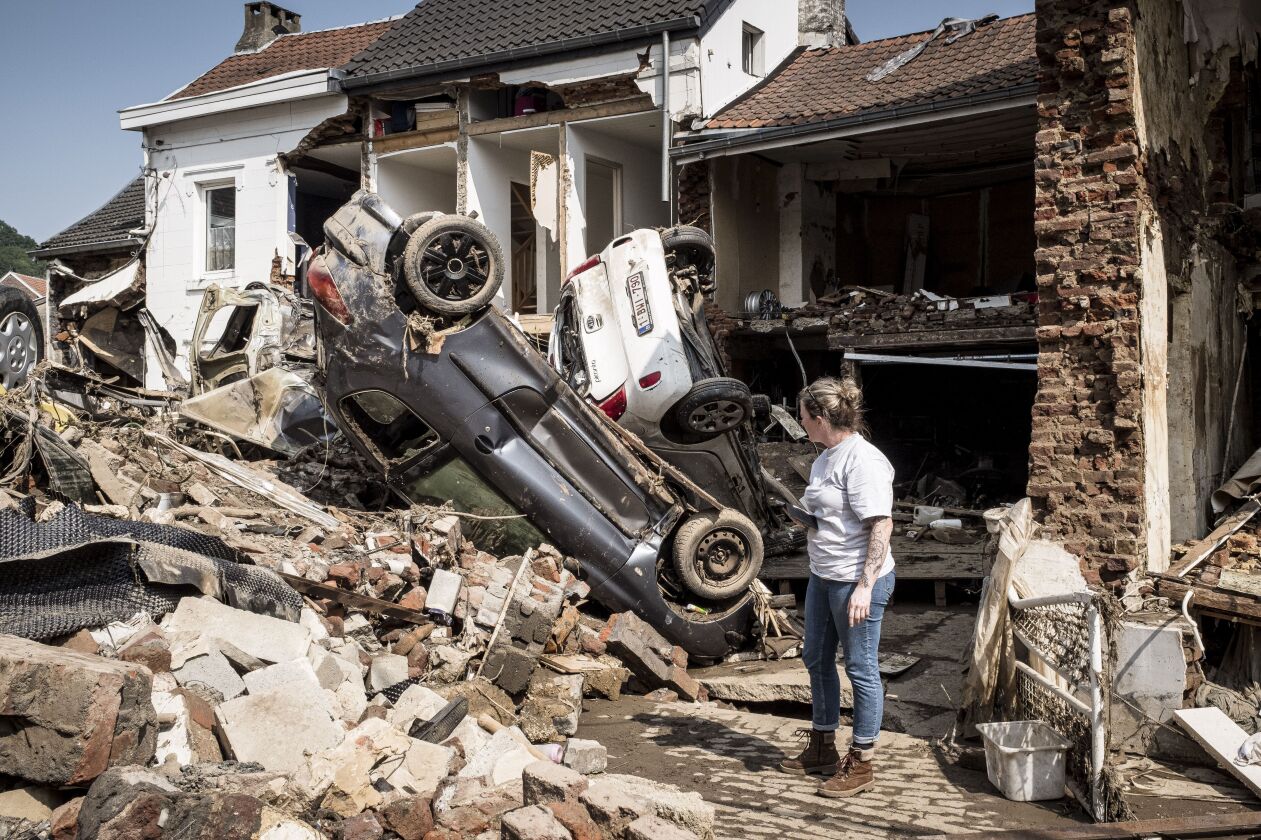 In this file photo dated Monday, July 19, 2021, a woman looks at cars and homes damaged after torrential rain caused flooding in Liege, Belgium.